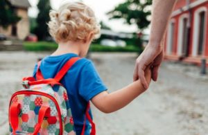 A small child holds the hand of his parent